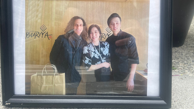 Eina Kwon (middle) and her husband{&nbsp;}Sung Kwon (right) pose with Kenny G at their restaurant{&nbsp;}Aburiya Bento House in this photo left at Eina's memorial in the Belltown neighborhood of Seattle on June 16, 2023. (KOMO News)