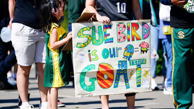 Vicky Chiong, 6, holds a Sue Bird sign with Olivia Chiong as they wait to enter Climate Pledge Arena before a WNBA basketball game between the Seattle Storm and the Washington Mystics, Sunday, June 11, 2023, in Seattle. Bird's jersey is set to be retired during a postgame ceremony. (AP Photo/Lindsey Wasson)