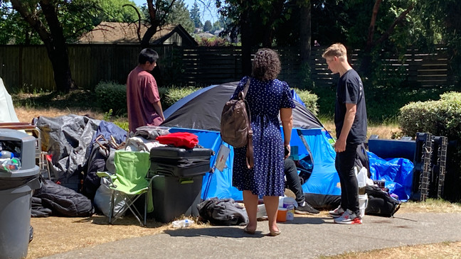 Social worker Stephanie Tidholm with REACH, (in blue dress) talked with people who pitched tents in Dottie Harper Park to see if there's any help REACH can provide them. (KOMO News){p}{/p}