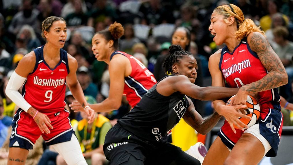 Washington Mystics center Shakira Austin (0) wrestles the ball away from Seattle Storm guard Jewell Loyd, second from right, during the first half of a WNBA basketball game Sunday, June 11, 2023, in Seattle. (AP Photo/Lindsey Wasson)